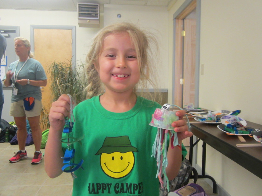 Camper showing her recycled crafts - toilet paper roll fish and applesauce container jellyfish