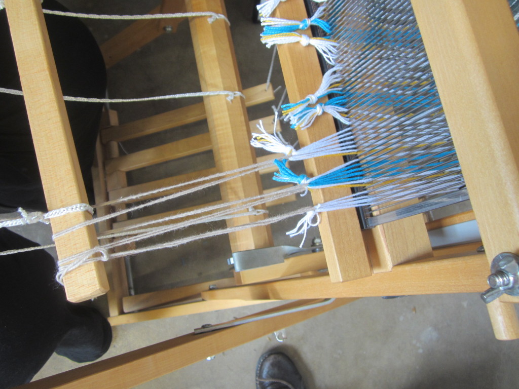 "Sewing" the pieces of warp to the apron stick