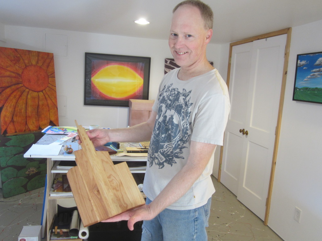 Dale Hoffmeyer in his home studio, holding one of his cutting boards made from recycled wood pieces