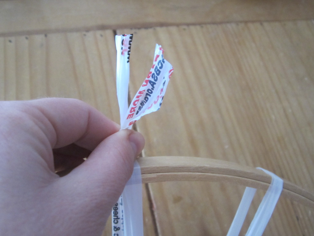 Cutting the plastic bag loop and tying it tight on the hoop