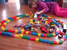 Girl playing with large plastic blocks and toy cars