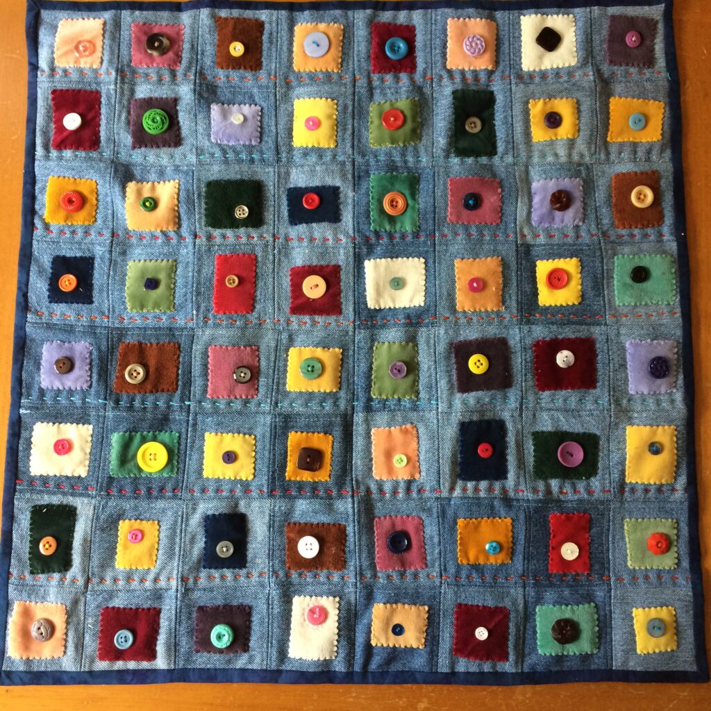 Square quilt made from denim scraps, upholstery samples (velvet) and buttons