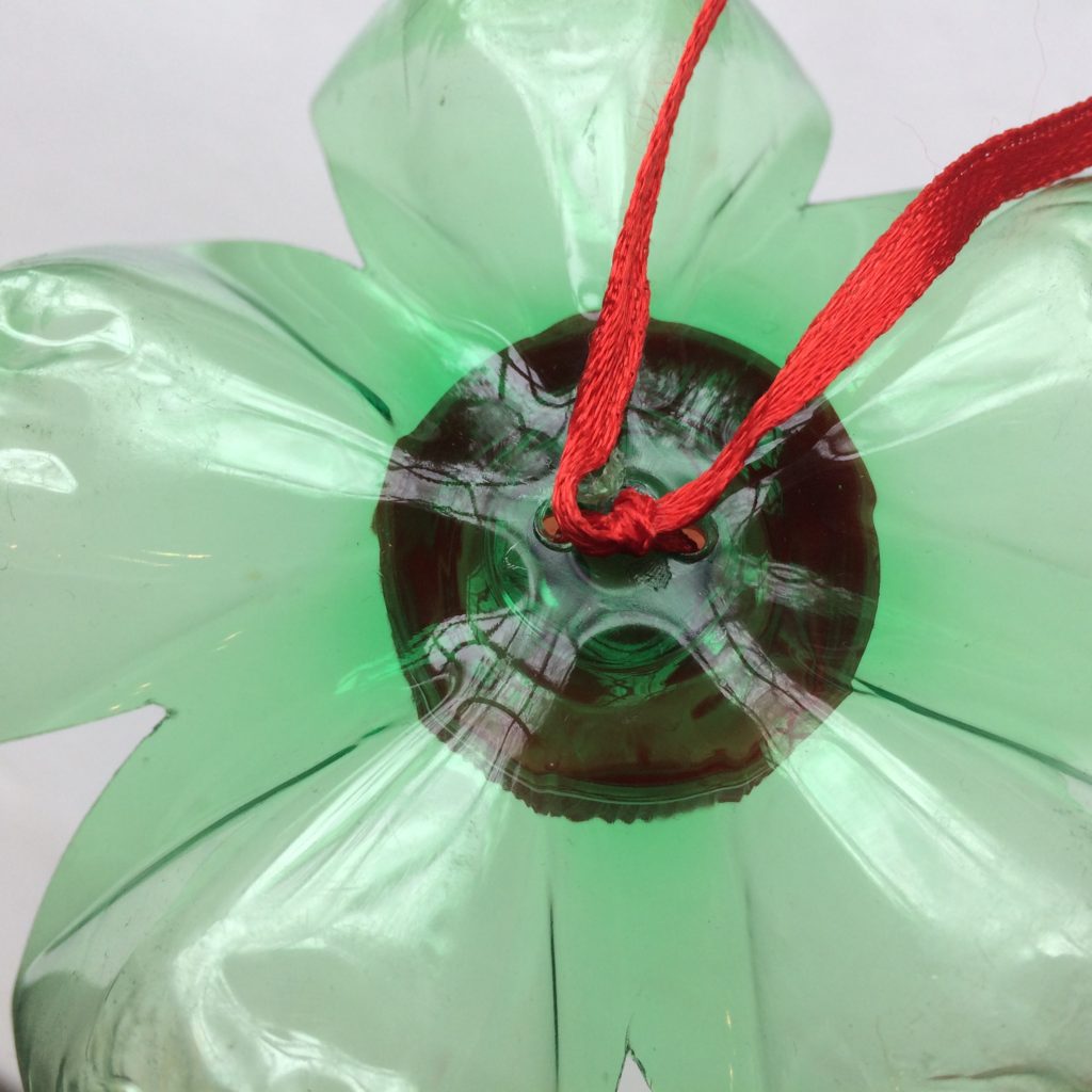 Close-up of the back of the decorative gift "bow" made from a recycled green soda bottle and cap