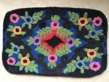 Rectangular hooked rug with pink, purple, blue and orange flowers in a traditional design