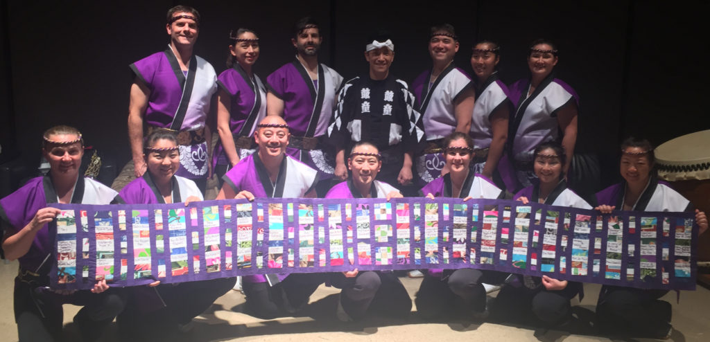 Members of Nen Daiko hold up a quilt showing the names of our supporters