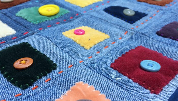 Denim quilt sewn with patches of velvet and decorative buttons