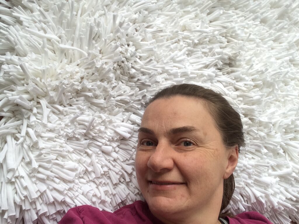 Happy Carla Brown from Trashmagination with her white rug woven from recycled t-shirts
