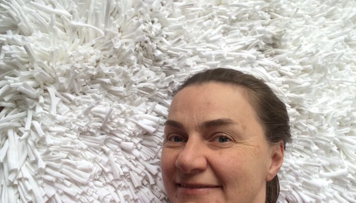 Happy Carla Brown from Trashmagination with her white rug woven from recycled t-shirts