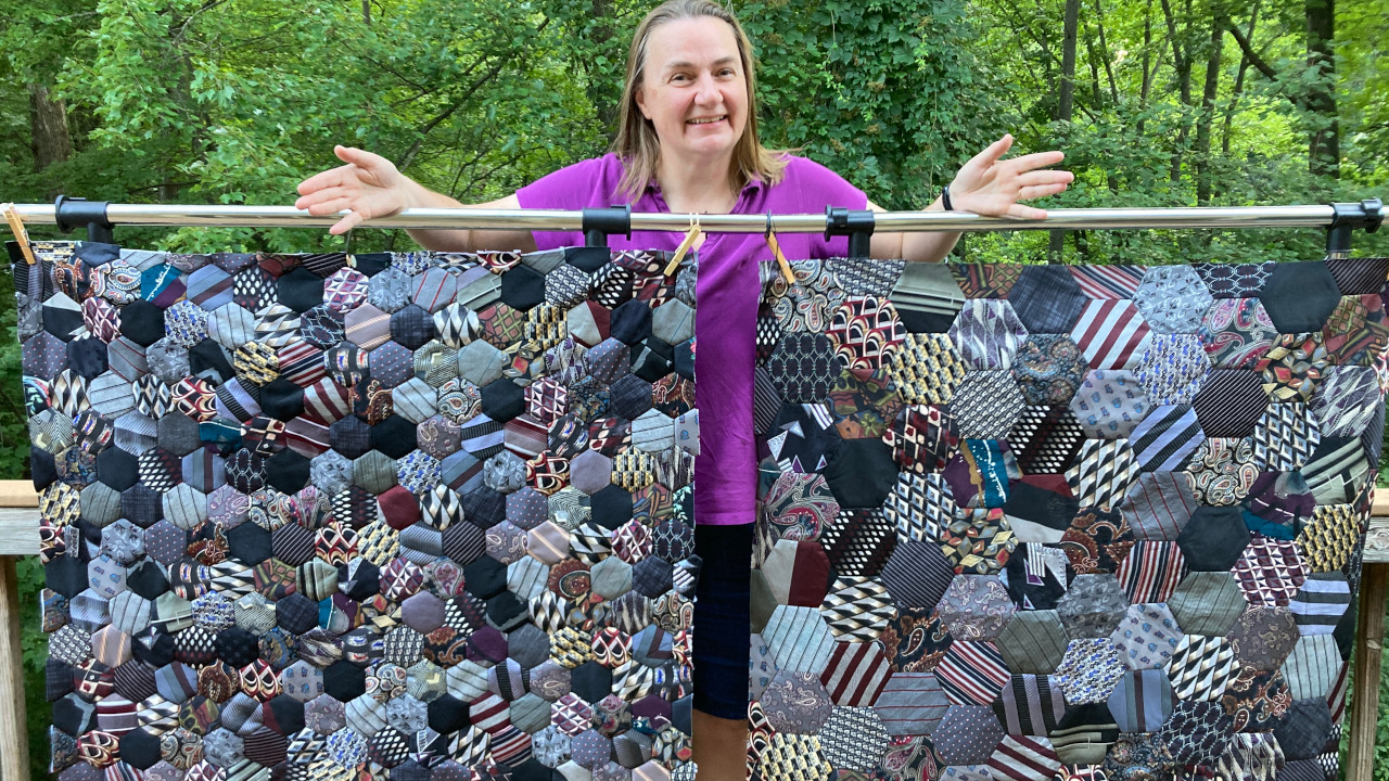 Two quilts side-by-side - one with smaller hexagons and one with larger hexagons. The quilts are blue, gray and black colors.
